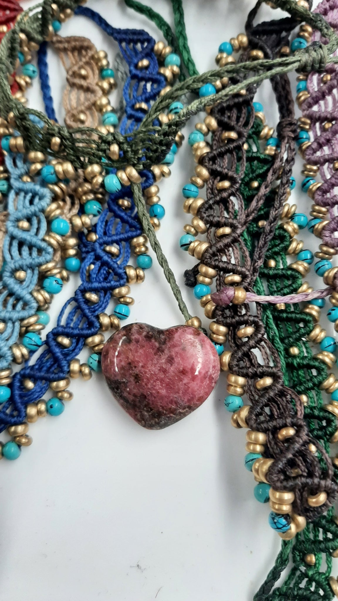 Close-up of a beaded necklace with a heart-shaped stone on a white background