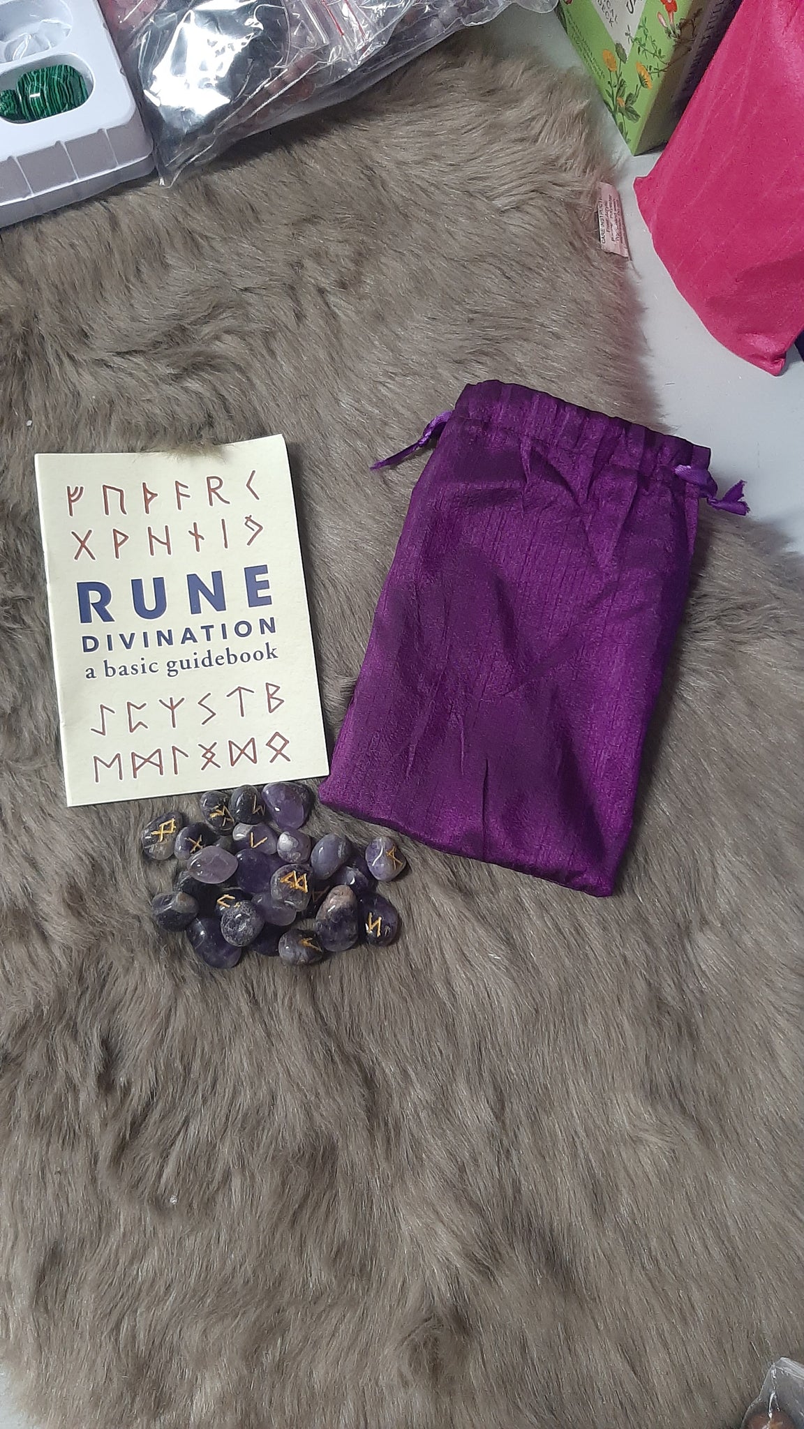 Purple drawstring bag with rune stones and a card on a textured surface