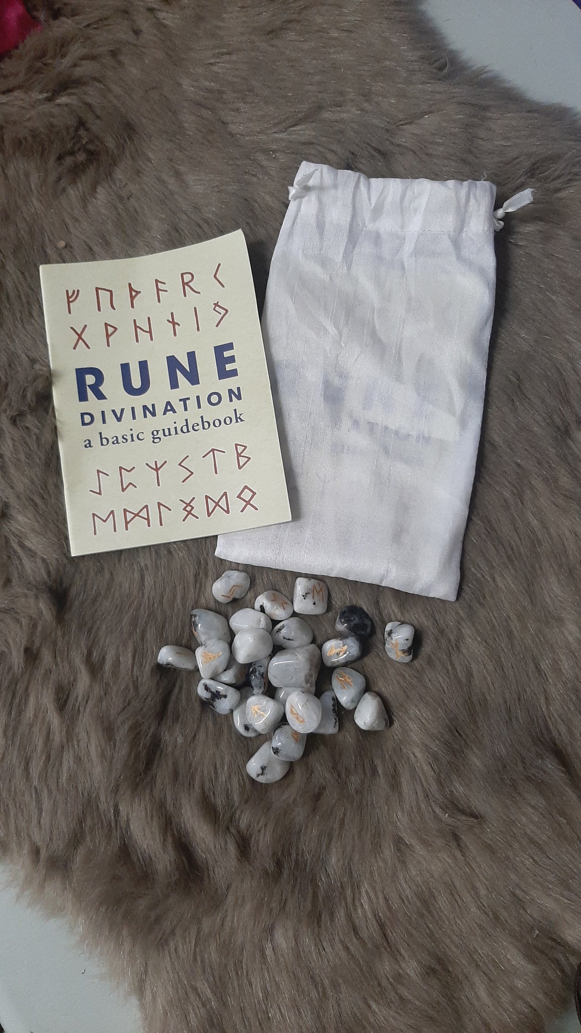 Runes book and stones on a fur surface
